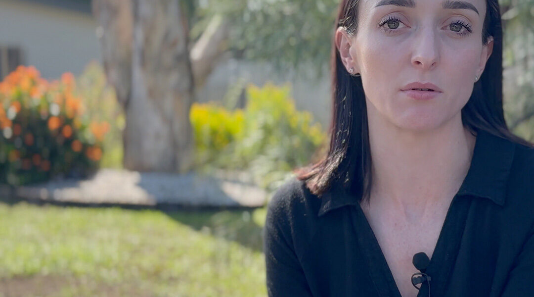 Programs Manager Brittany Faulkner sitting outside, with subtitles: Children are never not impacted by domestic violence.